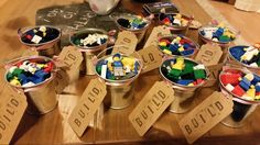 several buckets filled with lego blocks sitting on top of a wooden table