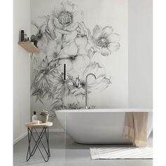 a white bath tub sitting next to a wall with flowers on it