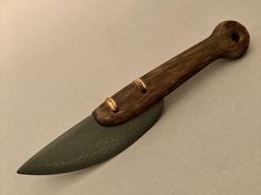 a knife with a wooden handle and green blade on a white tableclothed surface