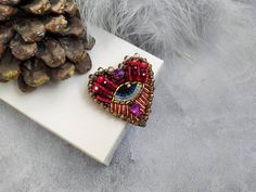 "Beautiful heart eye brooch is lovely handmade by me. 💓 This beautiful hand embroidered evil eye brooch took hours of precision and elaborate embroidery work. SIZE ~ 1,97\" x 1,97\" ( 5 cm x 5 cm) MATERIALS Made of czech seed beads and japanese seed beads, glass crystal, glass beads. Back side made of eco leather. Beaded jewelry requires careful and loving care. Avoid contact with hairspray, perfume, water, bleaches & lotions. Avoid over exposure to humidity, heat & sun. Gently wipe you Bohemian Brooch Pins For Gifts, Handmade Bohemian Brooch For Gifts, Handmade Bohemian Brooch As Gift, Handmade Bohemian Brooches As Gifts, Bohemian Handmade Brooches As Gifts, Bohemian Handmade Pins As Gift, Handmade Heart Shaped Brooches For Valentine's Day, Handmade Heart Brooches For Valentine's Day, Handmade Heart-shaped Brooches For Valentine's Day