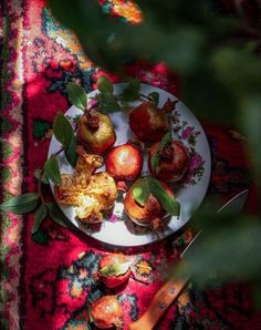 a white plate topped with apples on top of a red rug next to a knife and fork