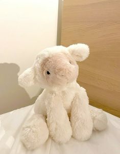 a white stuffed animal sitting on top of a bed