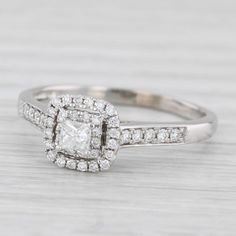 a white gold engagement ring with a square cut diamond surrounded by small round brilliant diamonds