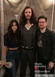 three people standing next to each other in front of a curtain