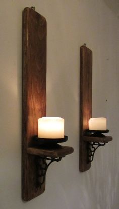 two candle holders are on the wall next to each other, one is made out of wood