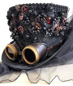 Steampunk Madhatter Hand made In black colour silk fabric Top Hat with leather covered embossed gears goggles with Red lens dial with 3D roses with Victorian brass embellishments angles on roof and black with net bows and bustle at the back of hat.  Please refer to the photos. The hat is lined with black satin. Front has copper Jewel cogs Details With Antique brass buckle.  Size Available in 55cm Please note this is full head hat and not mini hat)  Height of hat 18cm Thank you for looking Vintage Black Costume Accessories For Themed Events, Vintage Black Adjustable Costume Accessories, Black Adjustable Vintage Costume Accessories, Steampunk Black Halloween Hat, Black Steampunk Top Hat For Halloween, Steampunk Black Top Hat For Halloween, Black Steampunk Costume Hats And Headpieces, Black High Crown Costume Accessories For Themed Events, Black High Crown Accessories For Themed Events