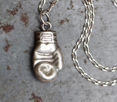 This striking necklace is such an unusual find, featuring an antique boxing glove pendant, roughly 23mm long and of pressed sterling silver and so quite light and comfortable to wear, bearing hallmarks at the bail. Dangles from a silver chain 16 inches long, also stamped 925 for sterling silver, and fastens with a classic round spring clasp. All in good solid vintage condition, beautifully and naturally aged, slightly oxidised with small amounts of original patina, and nicely weathered by time a Antique Box Chain Necklace As A Gift, Antique Box Chain Necklace Gift, Antique Box Chain Necklace For Gift, Antique Silver Hand Cast Necklaces For Gift, Gift Antique Silver Hand Cast Necklaces, Antique Silver Hand Cast Necklace As Gift, Antique Silver Hand Cast Necklace For Gift, Antique Box Chain Jewelry Gift, Boxing Glove