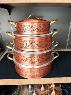 a stack of copper pots sitting on top of a wooden shelf