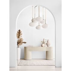 a white room with an arch and vases on the table