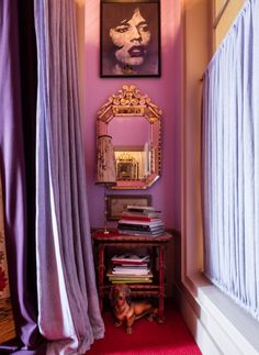 a pink room with curtains and a mirror on the wall next to a red rug