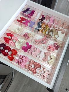 an open drawer with many different types of bows in it on top of a table