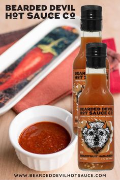 two bottles of bearded devil hot sauce next to a small bowl of pepperoni