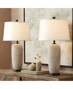 two white vases sitting on top of a wooden table next to a framed painting