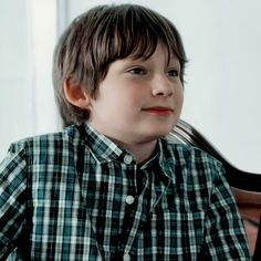 a young boy sitting at a table with a fork in his hand and looking to the side