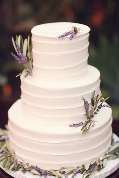 a white wedding cake with lavender flowers on top