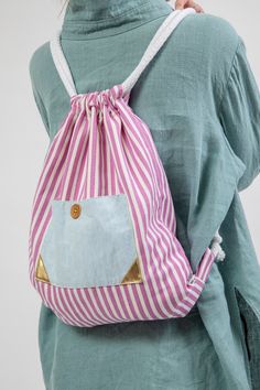 a woman wearing a pink and white striped bag with gold accents on the front pocket