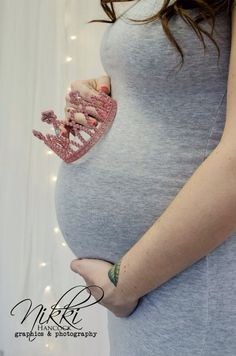 a pregnant woman is holding her belly in the shape of a crown