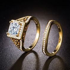 two gold rings with diamonds on them sitting next to each other in front of a black background