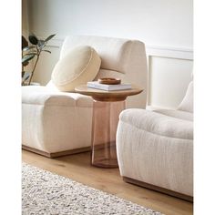 a living room with two white chairs and a round table on top of the floor