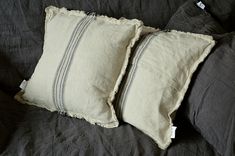 two pillows are sitting on a bed with black linens and one has a white stripe down the middle