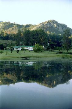 a large body of water sitting in front of a lush green hillside covered with trees