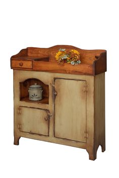 an old wooden cabinet with some flowers on it's top and the door open