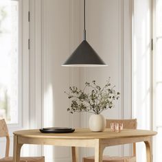 a dining room table with two chairs and a vase on the table next to it