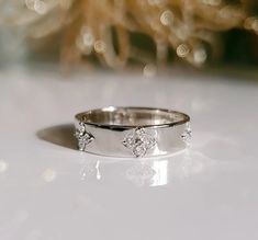 a white gold wedding band with three diamonds on the side, sitting on a table