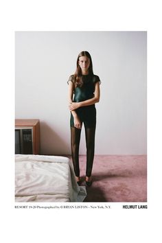 a woman standing in front of a bed wearing black tights and stockings with her hands on her hips