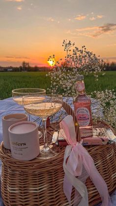 two glasses of wine sitting on top of a table next to bottles of alcohol and soap