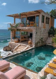 an outdoor swimming pool with chaise lounges next to it and the ocean in the background