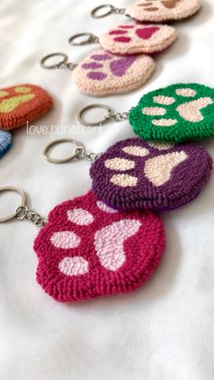 crocheted keychains with paw prints are lined up on a white sheet