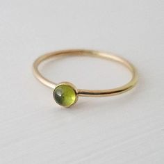 A single 4mm genuine peridot gemstone has been encased in 14k gold filled and set on a 14k gold filled stacker ring. Band measures 1.3mm thick. Stone measures 4mm. Dainty Gold Stackable Rings With Gemstones, Green Stackable 14k Gold Jewelry, Stackable Green 14k Gold Jewelry, Delicate Gold Stackable Birthstone Ring, Green Recycled Gold Jewelry For May Birthstone, Stackable Peridot Jewelry For Anniversary, Stackable Peridot Anniversary Jewelry, Green Birthstone Jewelry In Recycled Gold, Everyday Green Stackable Rings With Bezel Setting