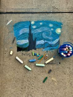 some crayons are laying on the ground next to an art project that looks like van gogh's starry night