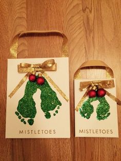 two hand and foot christmas gift bags on a wooden table with gold ribbon, red balls and green glitters