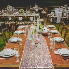 a long table set up with white plates, silverware and pink flowers in vases