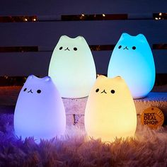 three lights that look like cats sitting in the grass next to each other on top of a pile of fake fur