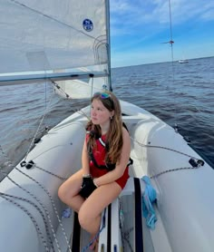 a woman sitting on the bow of a sailboat