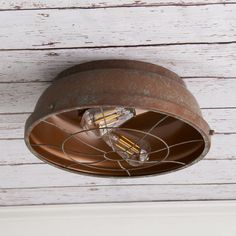 an old rusted metal light fixture on a white wooden wall