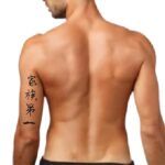 the back of a man with chinese writing on his left arm and chest, looking down