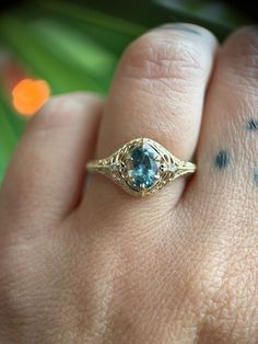 a close up of a person's hand wearing a ring with a blue stone