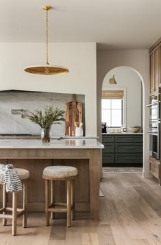 a kitchen with two stools and an island in the middle, surrounded by wooden cabinets