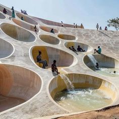 several people are sitting on the edge of a large water slide that has been designed to look like waves