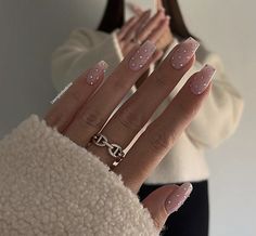 a woman's hand with pink and white polka dots on it, holding up her nails