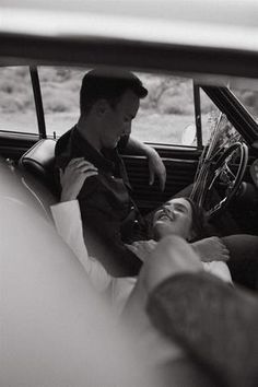 a man sitting in the back seat of a car next to a woman laying down