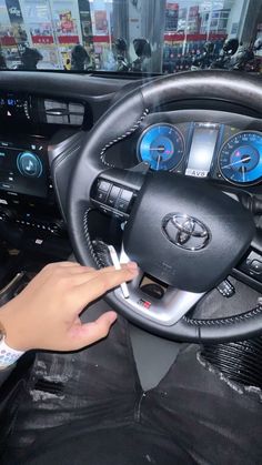 a person sitting in a car with their hand on the steering wheel