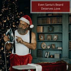 a man in santa's hat is reading a book next to a christmas tree