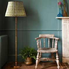 a wooden chair sitting next to a lamp on top of a hard wood floor near a potted plant