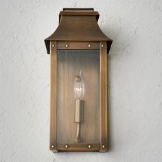 an old fashioned wall light on the side of a building with a candle in it