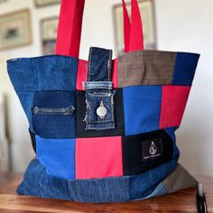 a multicolored tote bag sitting on top of a wooden table next to a wall